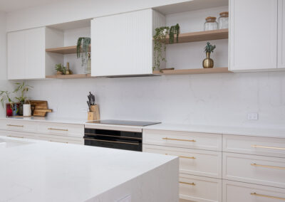 Modern minimalist kitchen with white cabinets, wood stools, and skylights.