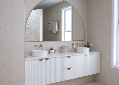 Modern minimalist kitchen with white cabinets, wood stools, and skylights.