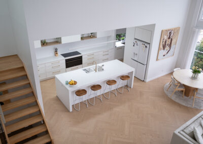 Modern minimalist kitchen with white cabinets, wood stools, and skylights.