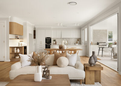 Modern white kitchen with a curved island, gold fixtures, built-in ovens, and an outdoor BBQ area