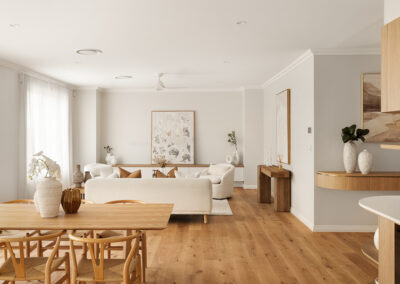 Modern white kitchen with a curved island, gold fixtures, built-in ovens, and an outdoor BBQ area