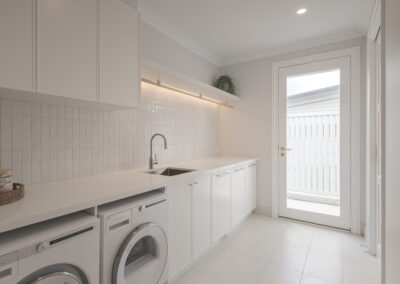 Custom white kitchen cabinetry with integrated storage and warm timber flooring in a modern Samford home