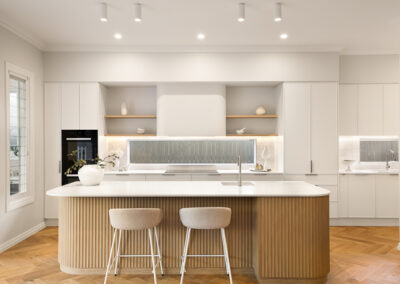 Custom kitchen in Grange with curved island detailing, soft neutral cabinetry and warm timber finishes