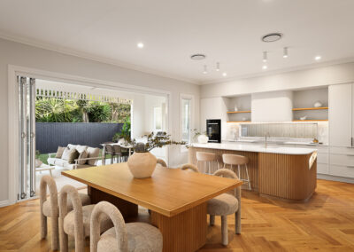 Open-plan kitchen and dining area in Grange with custom cabinetry, timber dining table and warm finishes