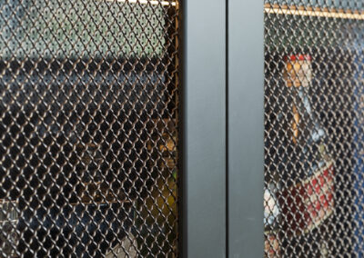 Close-up of mesh cabinet doors with black square knobs on custom bar cabinetry