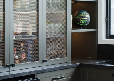 Custom bar cabinetry with mesh display doors, open shelves, black hardware and stone benchtop