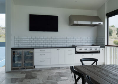 Custom outdoor BBQ kitchen with shaker cabinetry, bar fridge and tiled splashback by Zente Kitchens