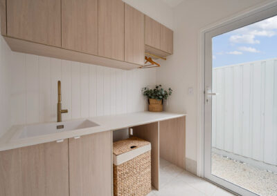 Custom laundry with Formica Soft Oak cabinetry, white stone benchtop and brass hanging rail