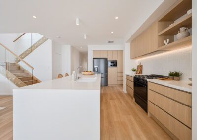 Coastal kitchen with white island, Laminex Aged Ash cabinetry, open shelves and integrated appliances