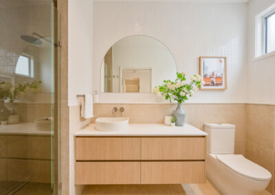Custom bathroom vanity with Laminex Aged Ash cabinetry, Zenith White Truffle stone and round mirror