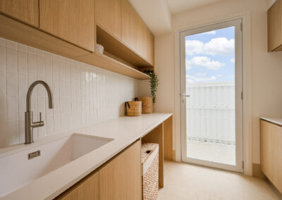 Laundry cabinetry with Laminex Aged Ash storage, white benchtop, sink and natural light