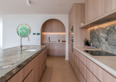 Galley kitchen with stone benchtop, timber cabinetry and arched drinks nook by Zente Kitchens