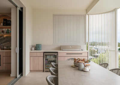 Outdoor entertaining area with custom BBQ cabinetry, dining table and balcony views