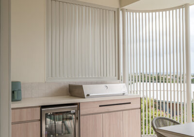 Custom outdoor BBQ cabinetry with bar fridge, timber-look fronts and balcony view