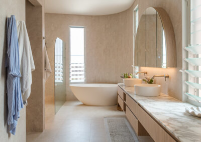 Long bathroom vanity with timber-look cabinetry, stone benchtop, freestanding bath and arched mirror