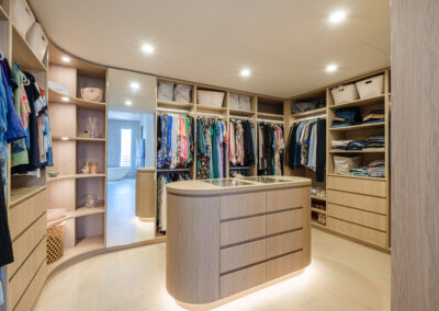 Large custom walk-in robe with island cabinetry, open shelves and hanging storage
