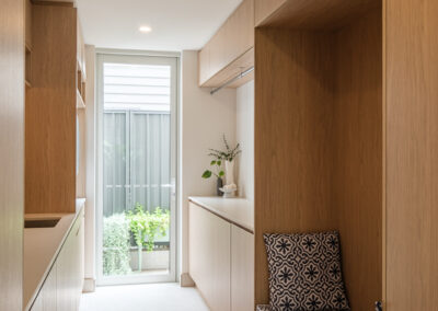 Custom laundry with timber-look cabinetry, long benchtop, open shelving and garden outlook