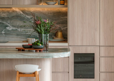 Coastal kitchen with stone island, timber-look cabinetry, arched bar nook and feature splashback