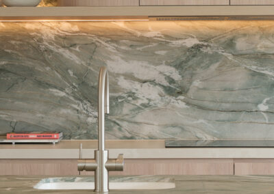Kitchen sink detail with stone island benchtop, chrome tap and feature stone splashback