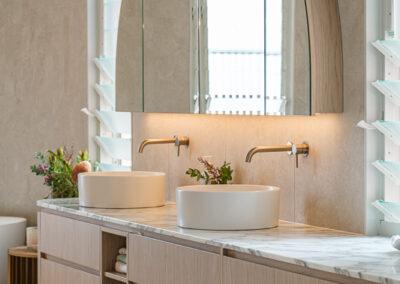Double bathroom vanity with arched mirrors, stone benchtop, timber cabinetry and twin basins